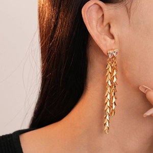 Detail view of gold tassel earrings with zircon hearts on a model for a stylish look