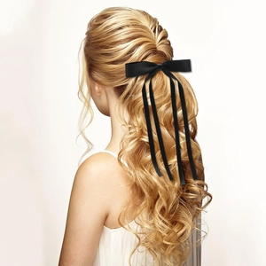 Detail of long black satin ribbon bow hair clip on blonde hair showing elegant texture