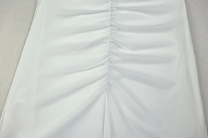 Detail of a white short sleeve dress featuring elegant vertical ruched textures