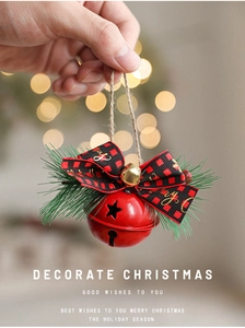 Close-up of red metal bell with buffalo plaid bow and pine needles for Christmas decor