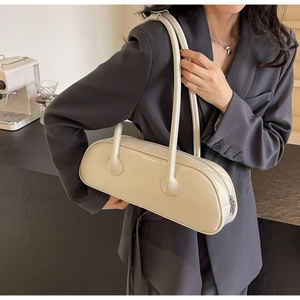 Model wearing a cream high-gloss shoulder bag with silver zipper and minimalist style