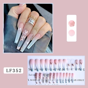 Detailed macro view of long ballerina press-on nails with pink gradient and butterfly gems