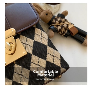 Detail of the argyle woven texture, brown leather flap, and golden metal lock on the bag
