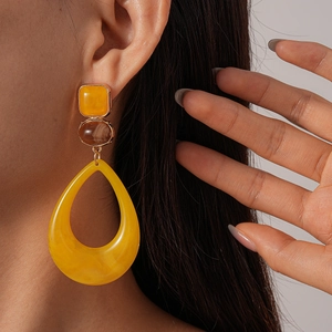 Close-up of model wearing yellow and brown resin geometric earrings with gold accents