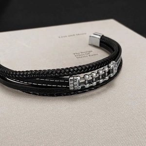 Detail of multi-layer black leather bracelet with silver chain accent and metal clasp