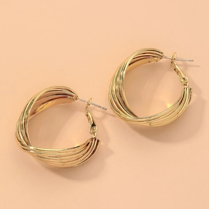 Macro shot of twisted gold hoop earrings with polished metallic texture and geometric design