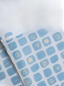 Detail of thermal transfer printing on a light blue mesh laundry bag with white patterns