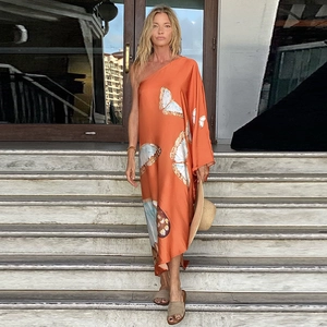 Detail eines orangefarbenen Maxikleids mit Schmetterlingsdruck und One-Shoulder-Design