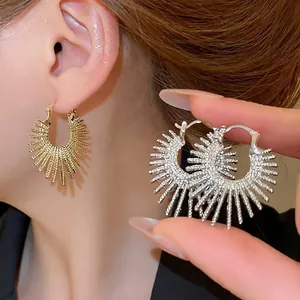 Modern gold and silver sunburst hoop earrings with irregular textured ray pattern