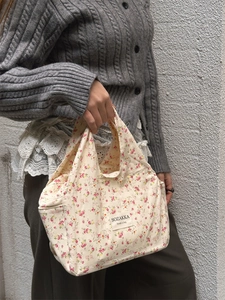 Close-up of beige floral canvas lunch bag with vintage flower pattern and woven label