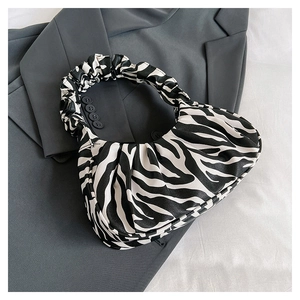 Close-up of zebra pattern cloud bag with pleated handle on a grey blazer backdrop