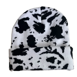 Detail view of winter knitted beanie featuring a classic black and white cow pattern