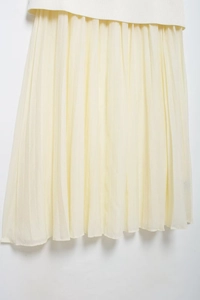 Detailed close-up of light yellow pleated skirt showing elegant chiffon fabric texture