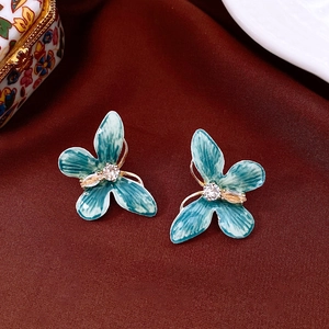 Détail de boucles d'oreilles papillon en émail bleu avec zircon sur velours