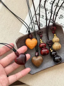 Macro shot of hand-carved wood gourd pendant with heart details and braided rope