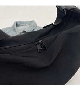 Close-up of the smooth black two-way metal zippers on a waterproof nylon crossbody bag