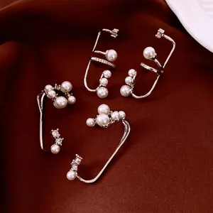 Set of four silver metal ear cuffs featuring elegant pearls and cubic zirconia on red velvet