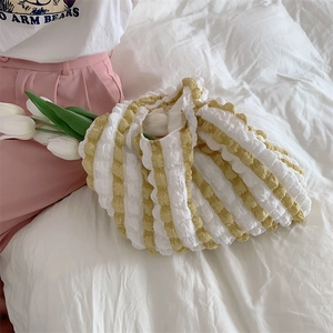Detail of yellow and white striped bubble texture tote bag on soft white bedding