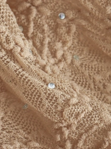 Gros plan sur un tissu en dentelle beige avec motifs fins et strass scintillants