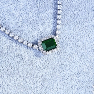 Macro shot of luxury emerald cut silver necklace on soft light blue velvet fabric