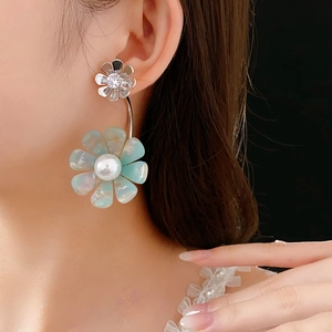 Detail of silver flower stud with blue acrylic petal and pearl drop on a model