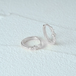 Macro shot of silver geometric hoop earrings with sparkling cubic zirconia on stone