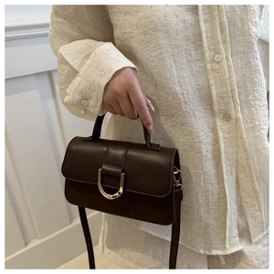 Detail of vintage brown handbag featuring a gold U-shaped metal buckle and smooth leather