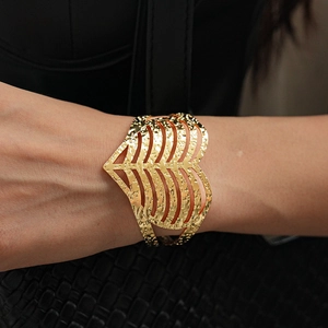 Close-up of a large hollow heart cuff bracelet with a hammered gold metal texture