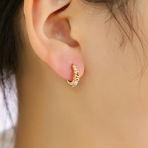 Détail des boucles d'oreilles 520 en or avec strass étincelants portées sur l'oreille