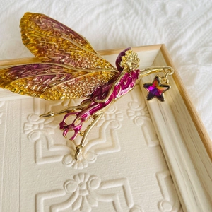 Detailed view of enamel fairy brooch with purple gradient wings and star pendant