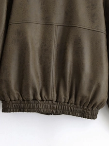Detailed view of brown distressed leather jacket with elastic hem and stitching
