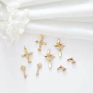 Detailed close-up of gold-plated zircon charms featuring cross, key and heart shapes