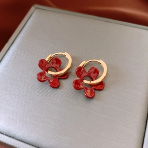 Gros plan de pendentifs fleurs en émail rouge sur des boucles d'oreilles dorées