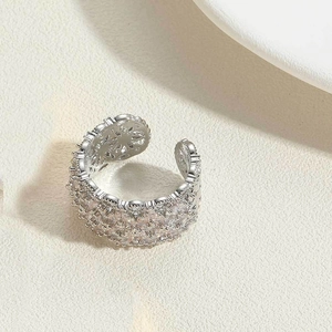 Macro detail of adjustable silver ring with hollow flower design and zircon inlay