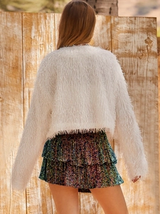 Vista posterior de minifalda de lentejuelas con chaqueta blanca de flecos de piel sintética