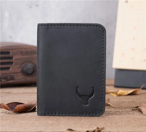Macro detail of black leather card holder with vintage cow logo and stitching on wood