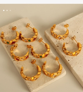 Macro detail of gold-plated C-shaped earrings with colorful square natural stones