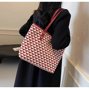 Classic red houndstooth tote bag with leather strap styled on a black coat back view