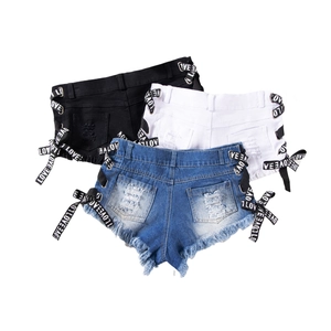 Dettaglio degli shorts in denim a vita alta con lacci laterali e bordi sfrangiati