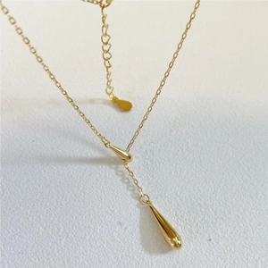Minimalist gold Y-shaped necklace featuring dual teardrop pendants on a beige surface