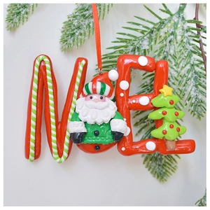 Detailed view of NOEL resin ornament with Santa Claus and bow on snowy pine branch