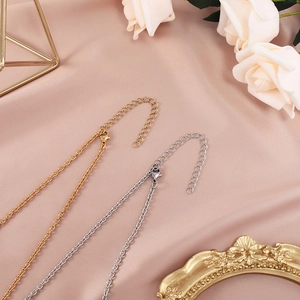 Detail of gold and silver stainless steel chains with lobster clasps on pink silk background