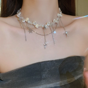 Détail d'un collier superposé avec perles baroques et pendentifs en forme d'étoile