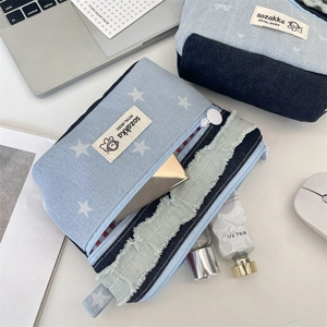 Detail of patchwork denim makeup bag with star pattern, white zipper, and fringe trim