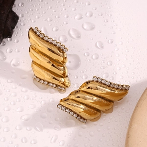 Dettaglio di orecchini ad ala placcati oro 18K con texture ondulata e zirconi