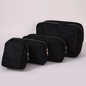 Set of four black nylon cosmetic bags with gold zippers in various sizes for travel