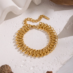 Détail d'un bracelet tressé en acier inoxydable doré avec un fermoir mousqueton sur fond blanc