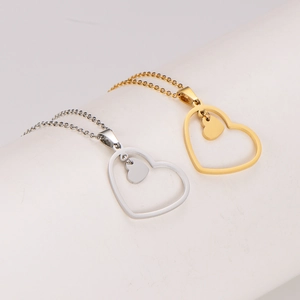 Gold and silver hollow heart necklaces in stainless steel on white pedestal