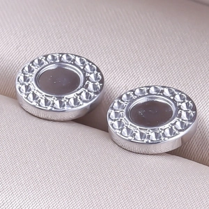 Macro shot of silver 304 stainless steel stud earrings with textured circular metal edges