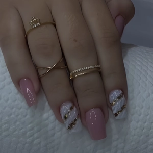Macro detail of gold crown and crisscross rings with pink marble gold foil press-on nails